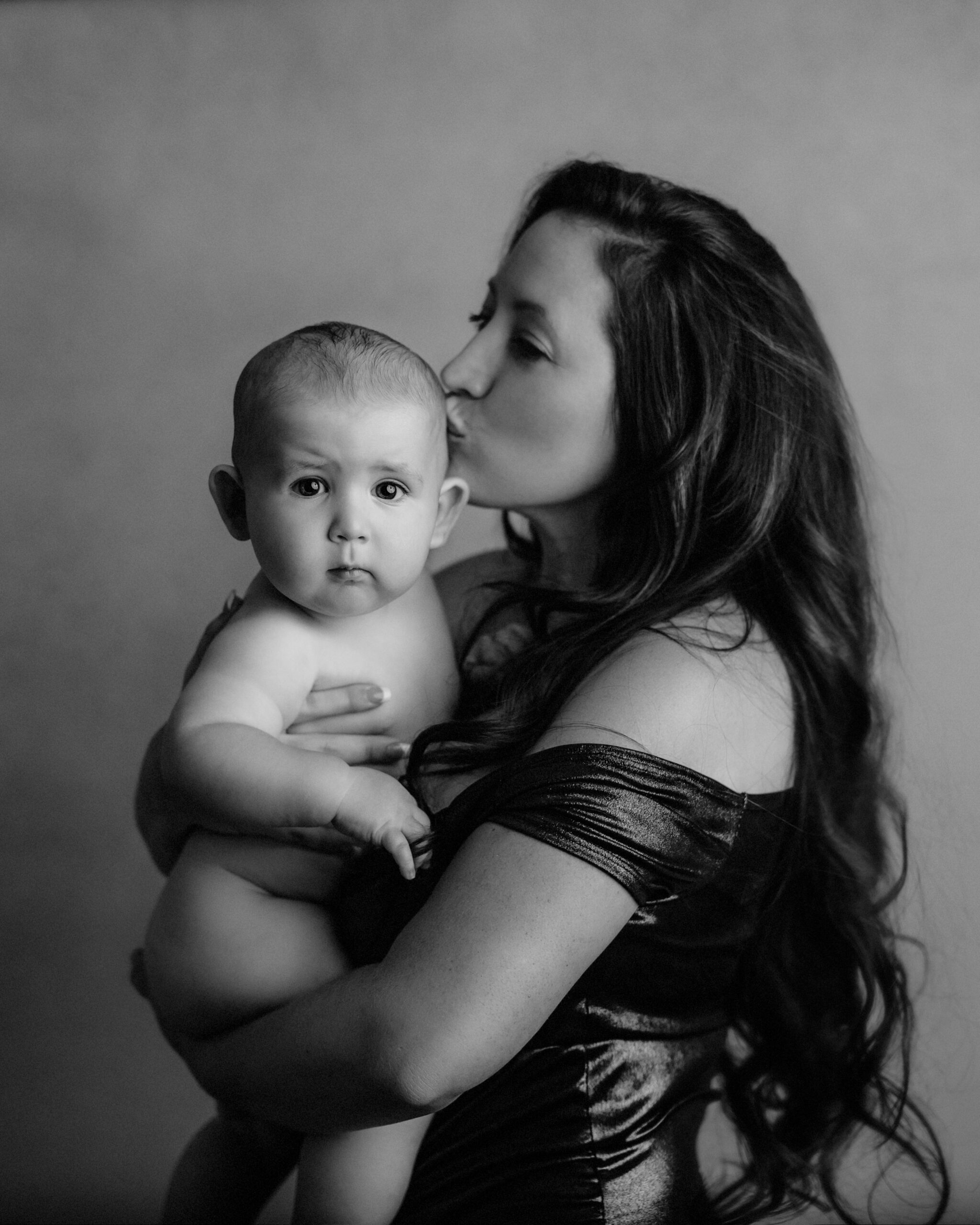 mom kissing baby in black and white