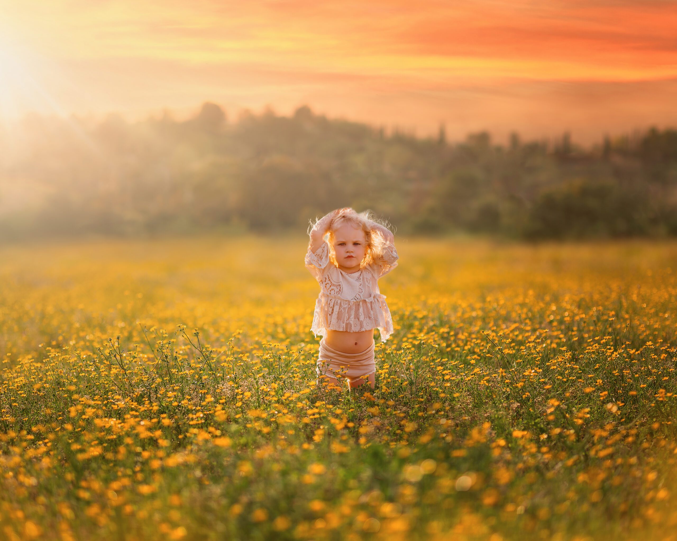 child standing in a field of yellow flowers with sunshine